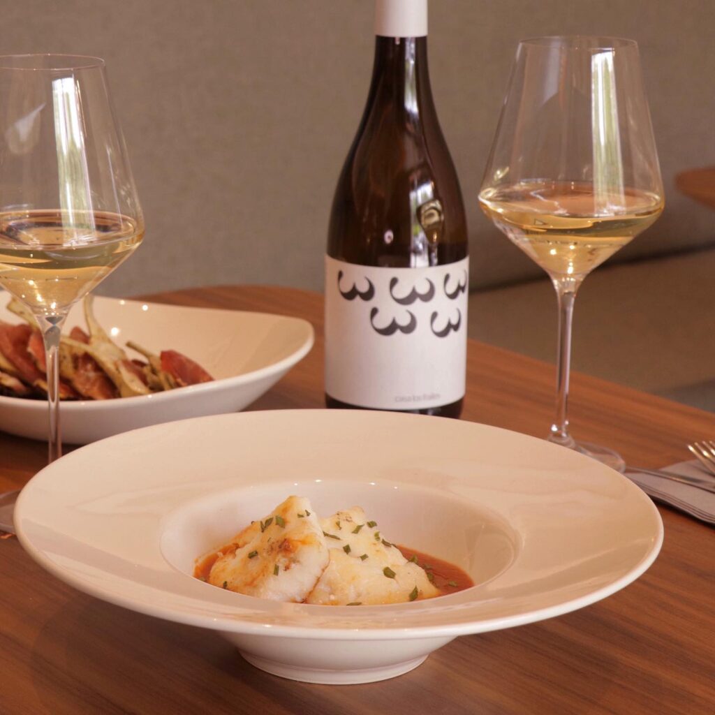 bacalao, tierno y sabroso, con su salsa casera, acompañado de una botella de vino blanco